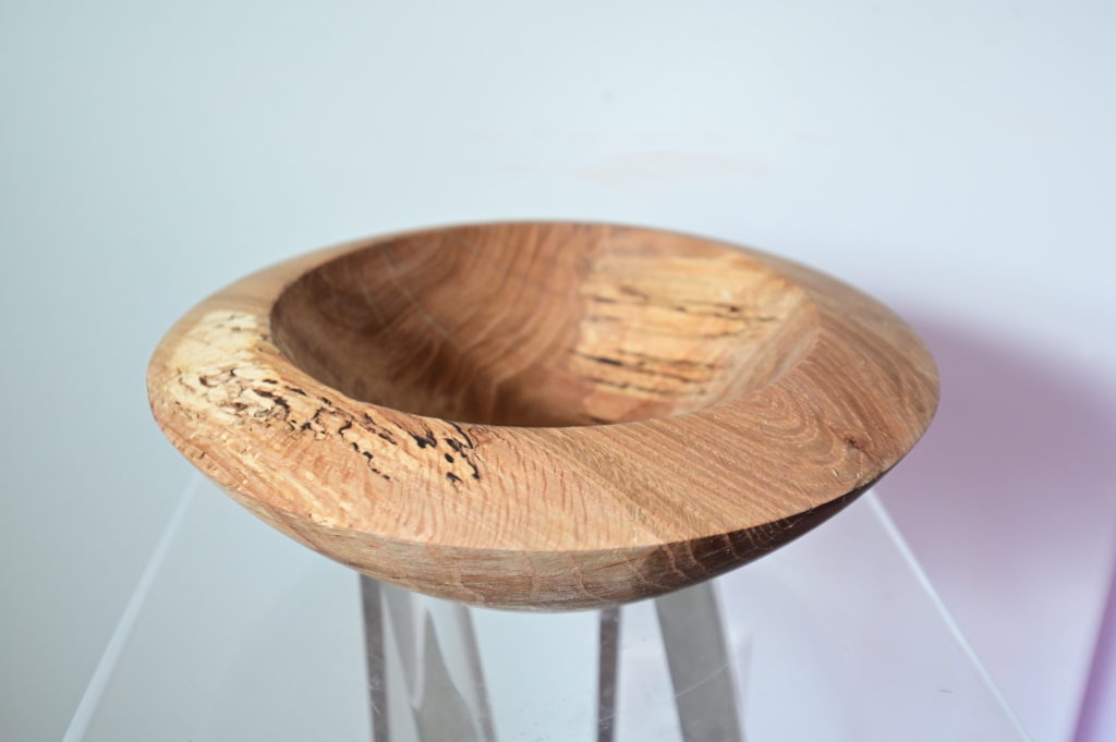 a sculpted wooden bowl on a lucite pedestal