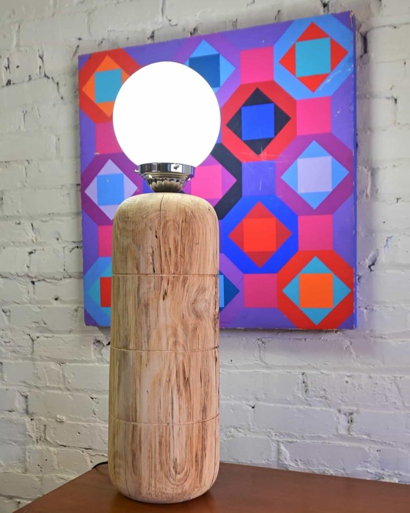 an art gallery with artistic wooden table lamp and modern art on wall