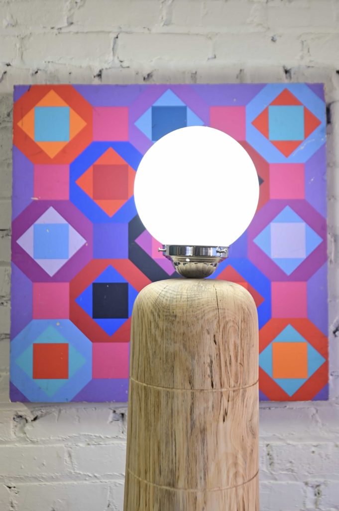 a midcentury modern lamp and post modern art piece on wall